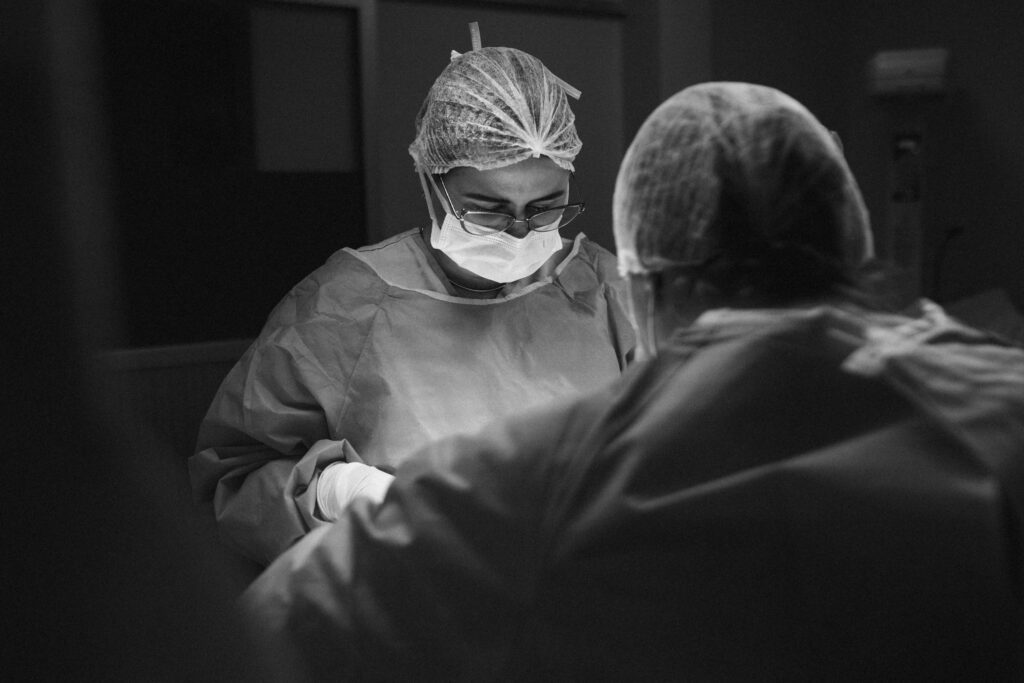 Two surgeons operate under focused lighting in a sterile environment.